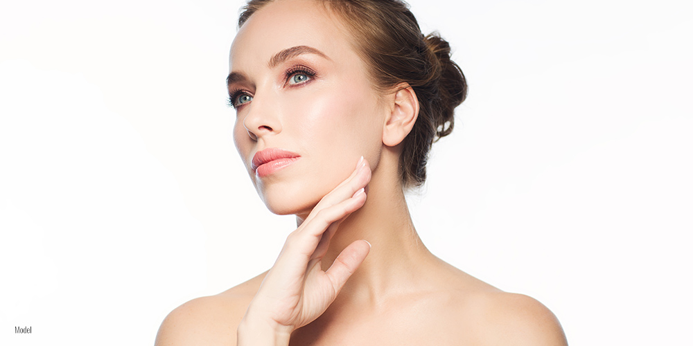 A portrait of a woman's face, looking off to the side and holding one hand underneath her chin.